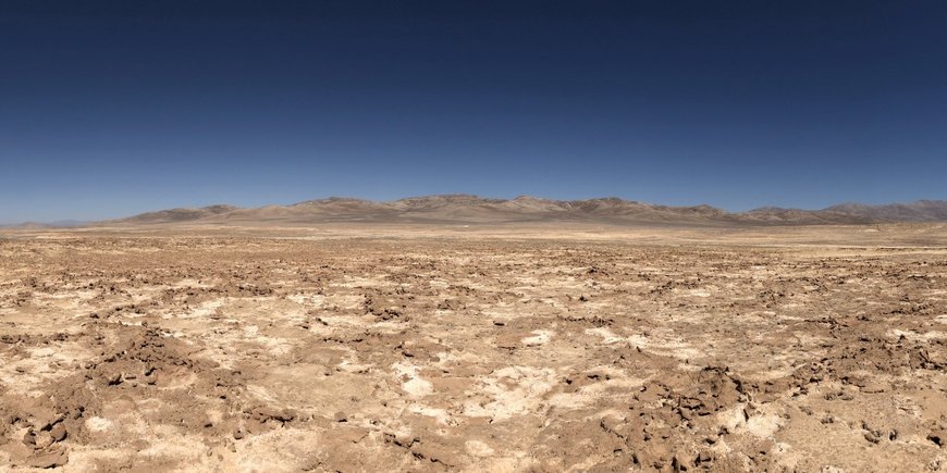 Wüstenlandschaft mit Hügeln und einem ausgetrockneten Seeboden.